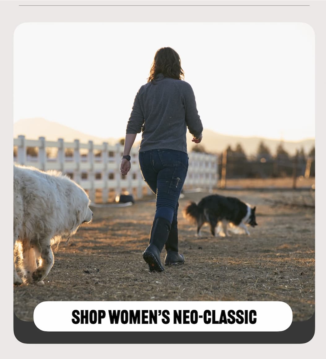 A woman walking with her two dogs wearing black neo-classic tall farm boots