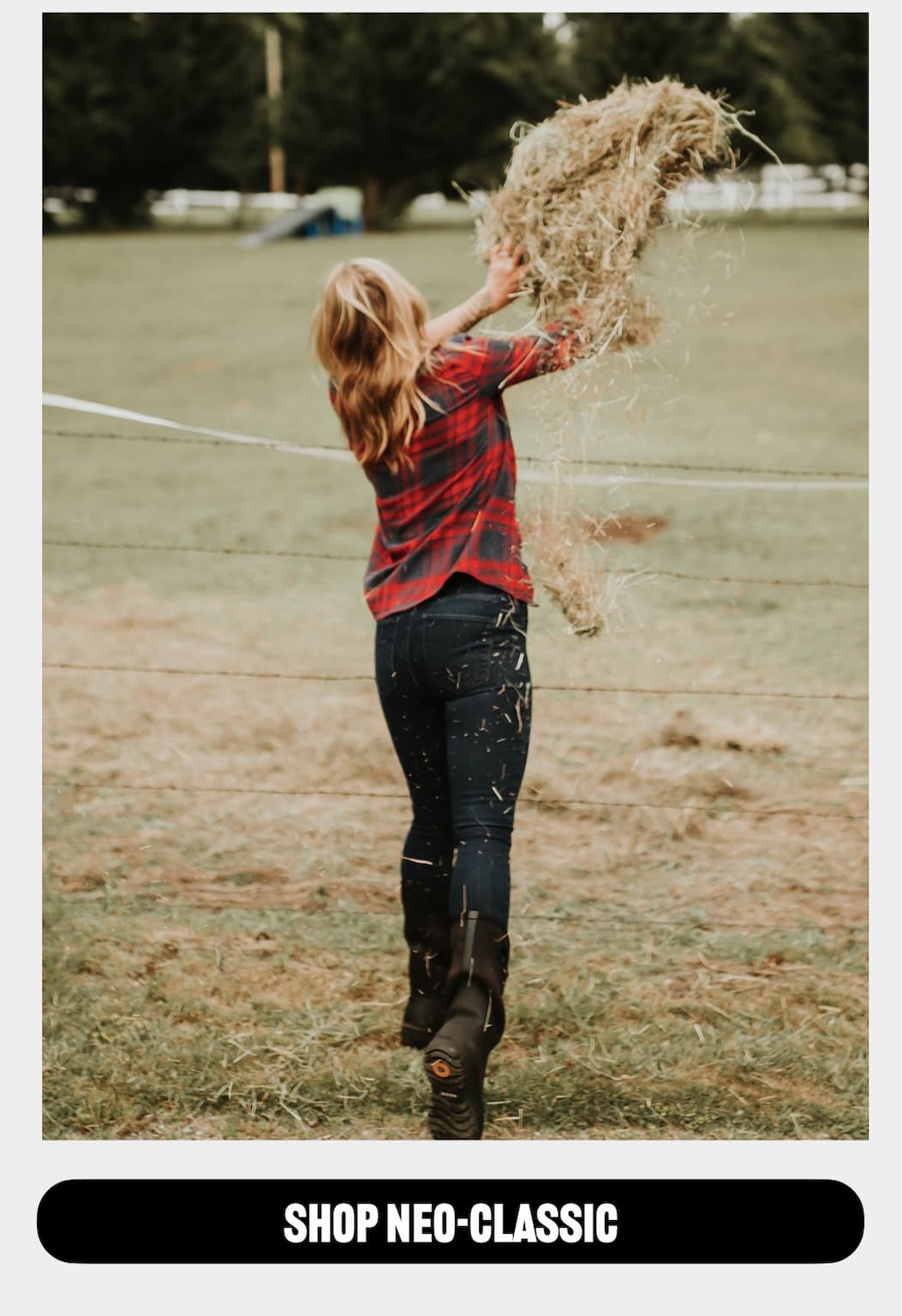 A woman throwing hay over a fence wearing the Neo-Classic tall in black. Shop this style. 