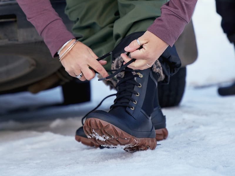 A woman lacing up her Arcata Trek winter boots.