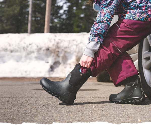 Kids pulling on their Kids Classic Seamless boots in black