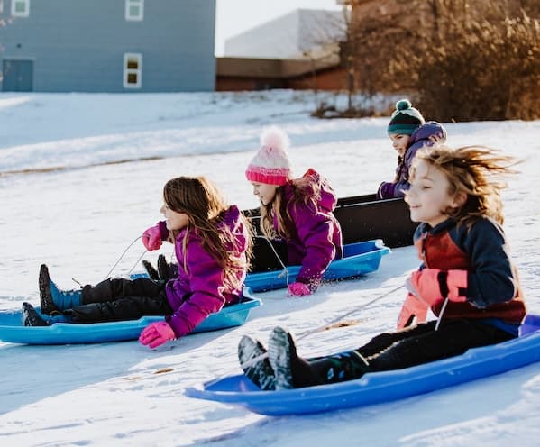 4 Kids' sledding down a hill wearing BOGS winter boots