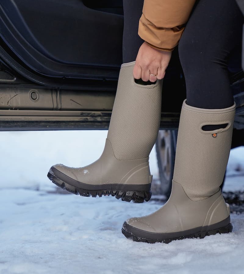 A woman pulling on a pair of whiteout boots