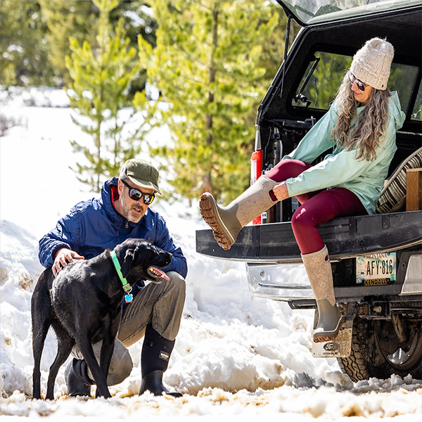 Man petting a dog and a woman pulling on her boots
