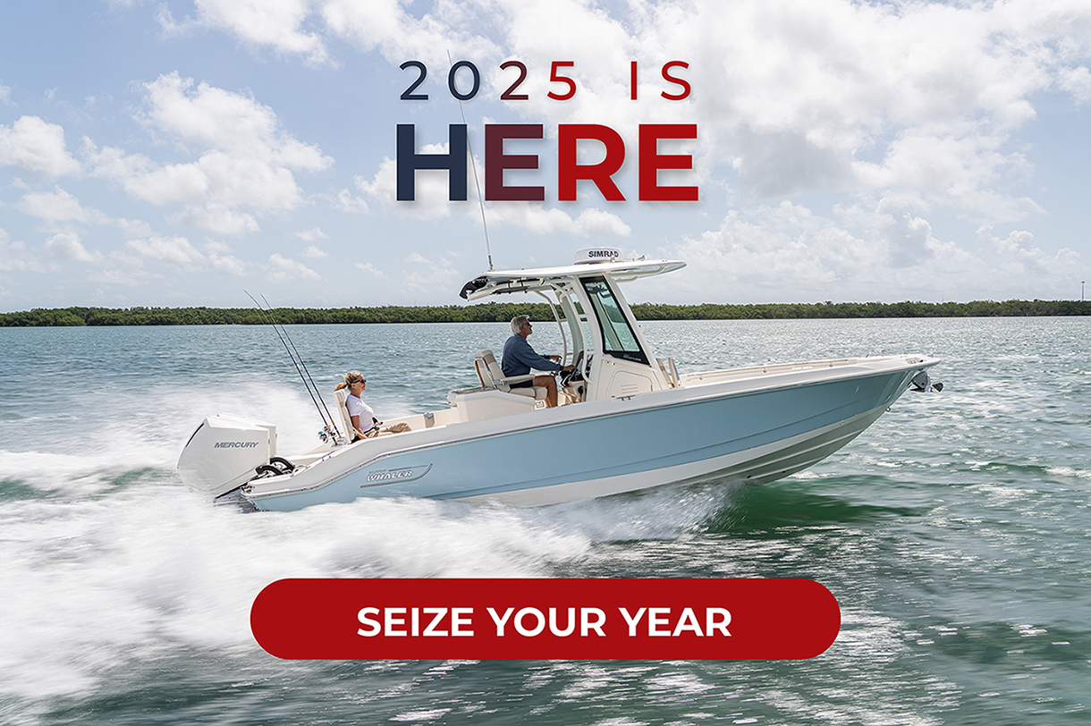 A couple enjoys a ride on a Boston Whaler light blue and white boat that speeds through the water.