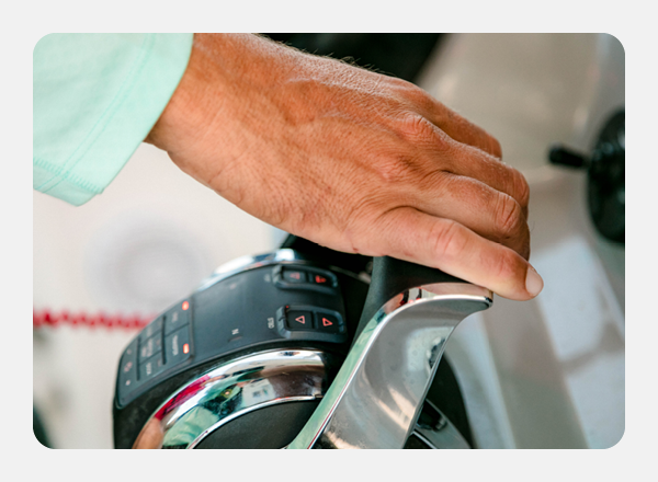 Close-up of a hand on a boat's control lever with chrome accents.