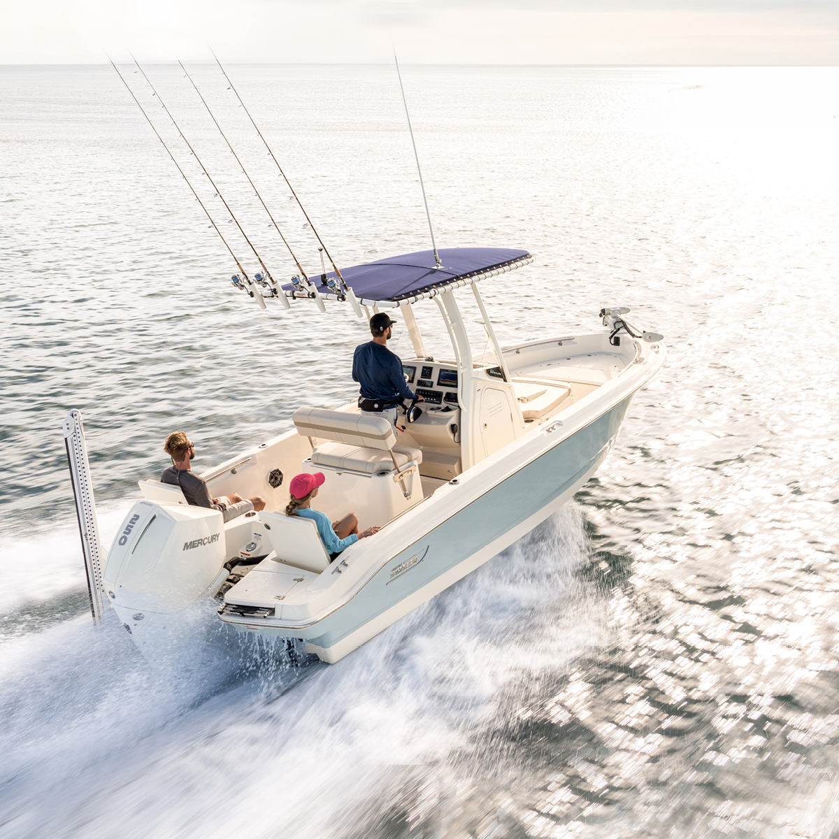 A family of three enjoys a sunny day fishing on a boat, with the father steering and fishing rods racked.