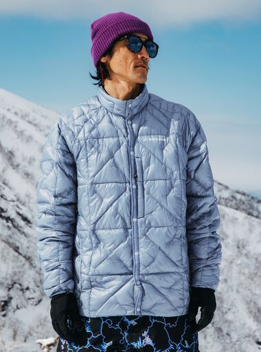The Men's Burton [ak] Baker Ultralight Down Jacket in blue on a model in the mountains