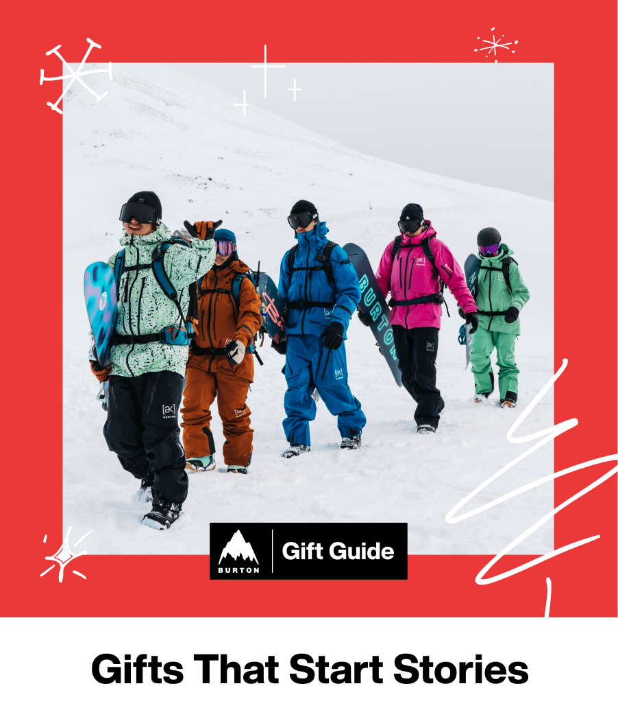 5 Burton riders wearing [ak] Outerwear in different colors and prints hiking across the snow carrying their Burton snowboards with the text 'Gifts that Start Stories'