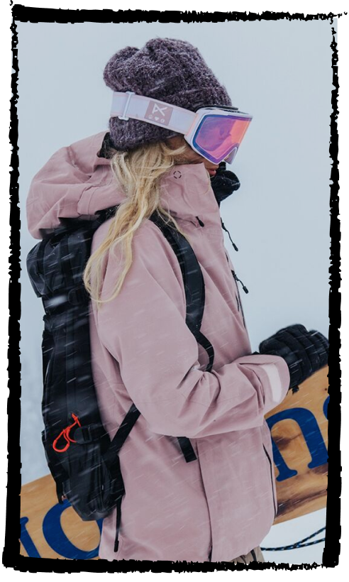 Anna Gasser wearing the [ak]® Upshift jacket in shadow pink while carrying a Burton Snowboard