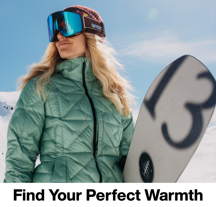 Burton rider wearing the [ak] Baker down jacket in sage green carrying the Burton Family Tree Hometown Hero snowboard on a mountain in the sun. The text 'Find Your Perfect Warmth' is underneath.