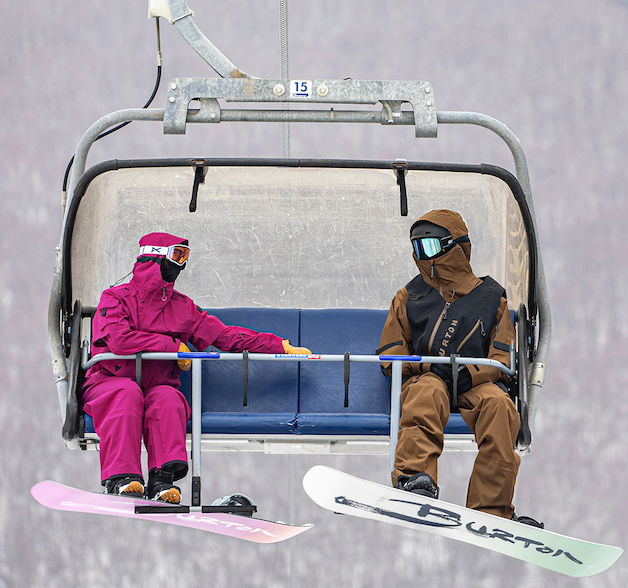 Two riders wearing Year of the Horse outerwear riding the chairlift.