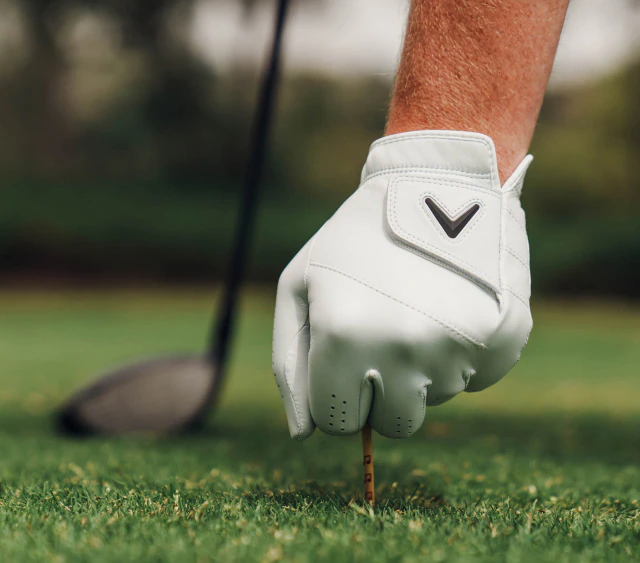 Golfer setting tee while wearing Tour Authentic Glove