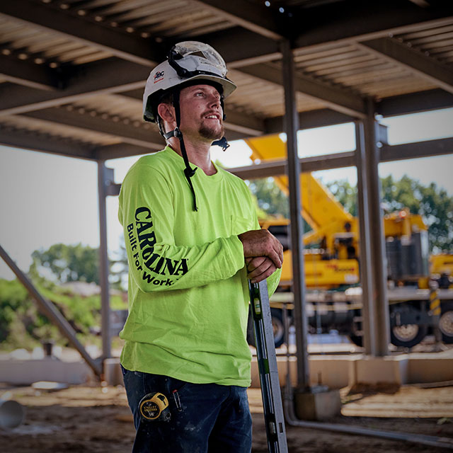 A man wearing the Carolina Hivis Logo long sleeve t-shirt in yellow. Shop men's apparel.