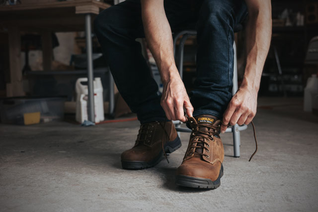 A man lacing up his Bruno 6" Waterproof Broad Toe Work Boot in brown. Shop men's lace up boots.