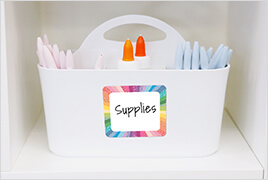Crafty and Cool name tag placed on a white, plastic supply bin on a shelf.