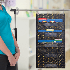 Teacher standing next to a Gold Stars File Folder Storage pocket chart in a classroom.