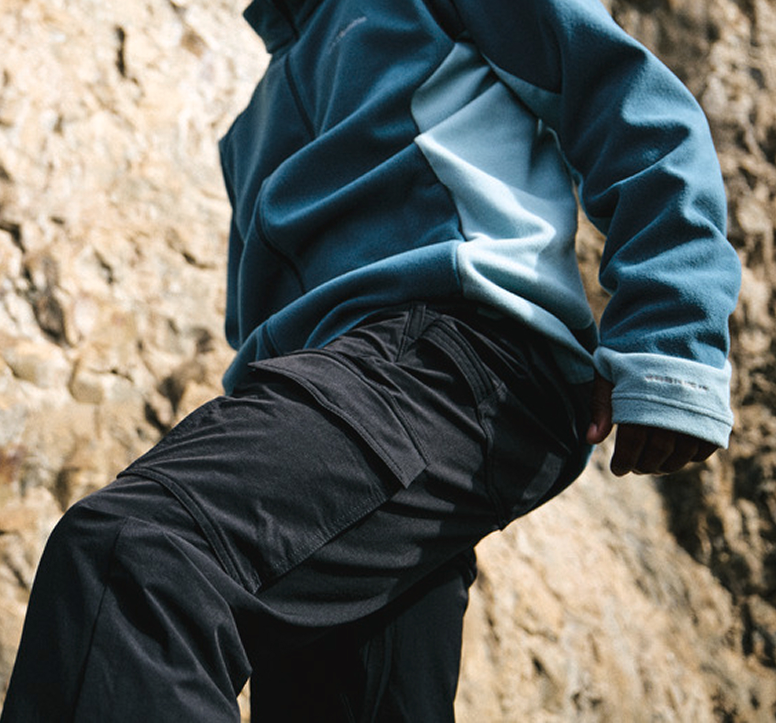 A close-up image of a hiker wearing a fleece and cargo pants.