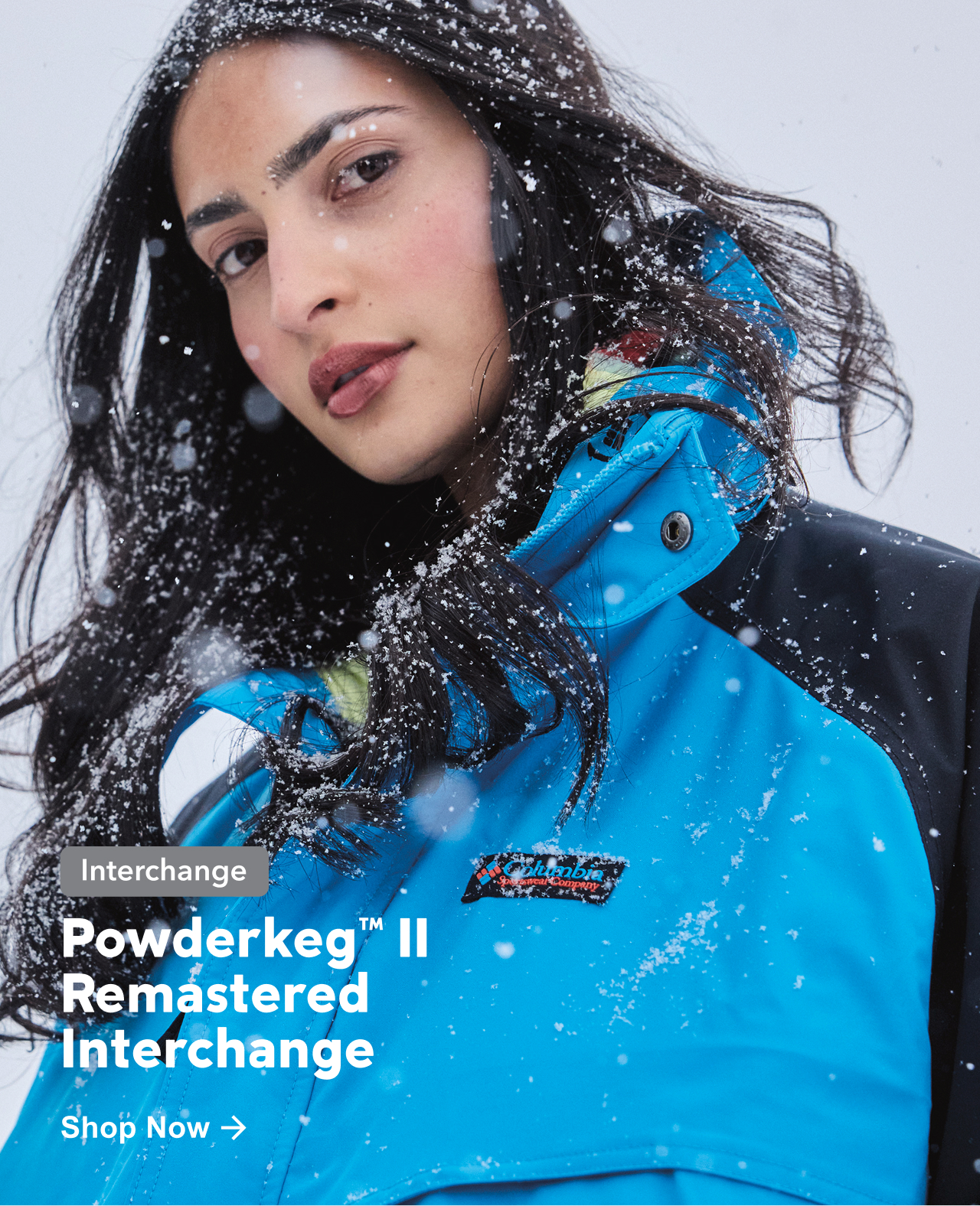 Powderkeg Two Remastered Interchange jacket in blue on a model with snow falling on her.