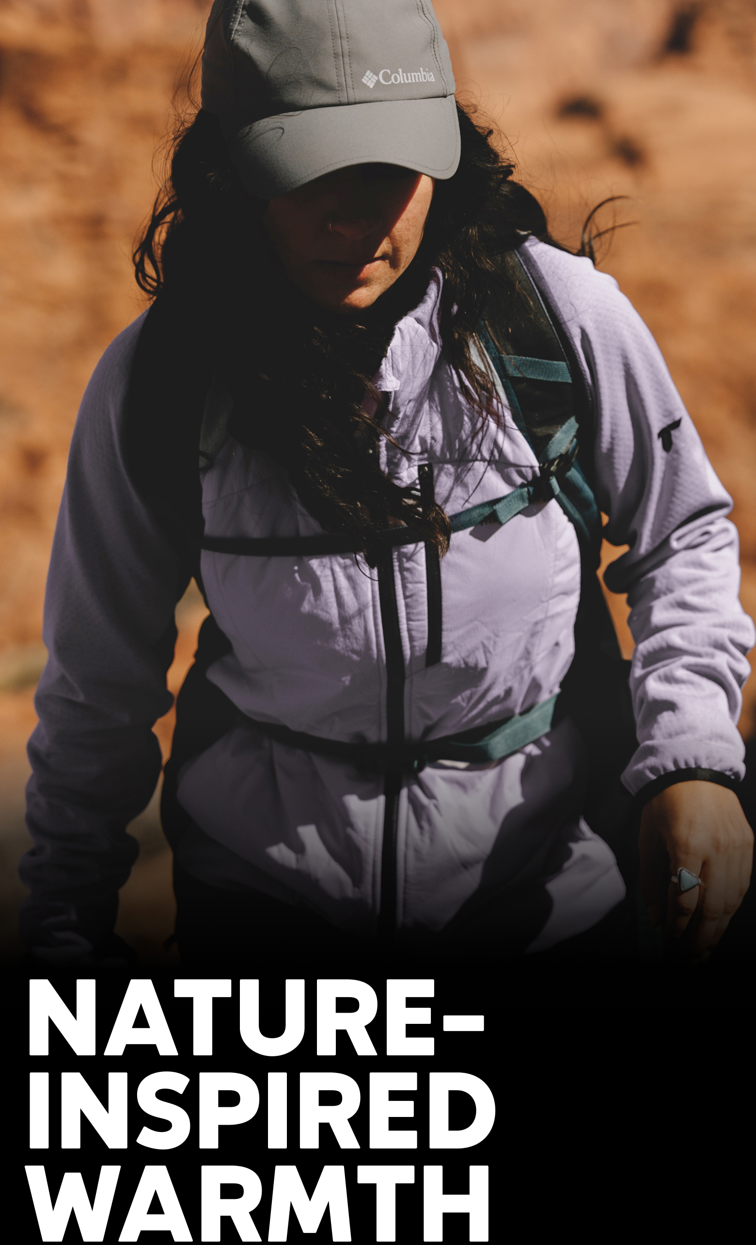 A woman wearing a purple jacket as she hikes in a canyon.