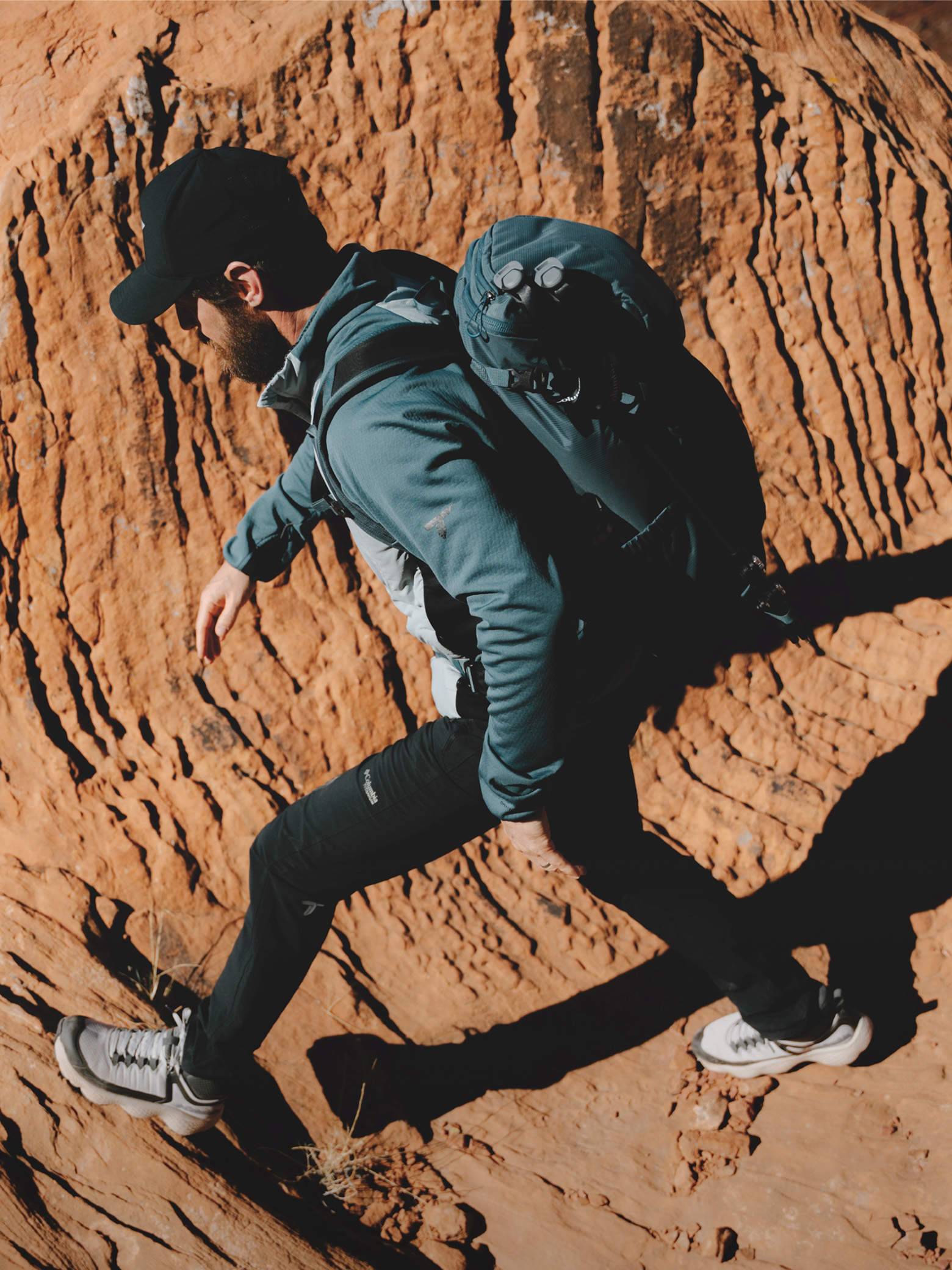 A man hiking in a canyon wearing a jacket and backpack.