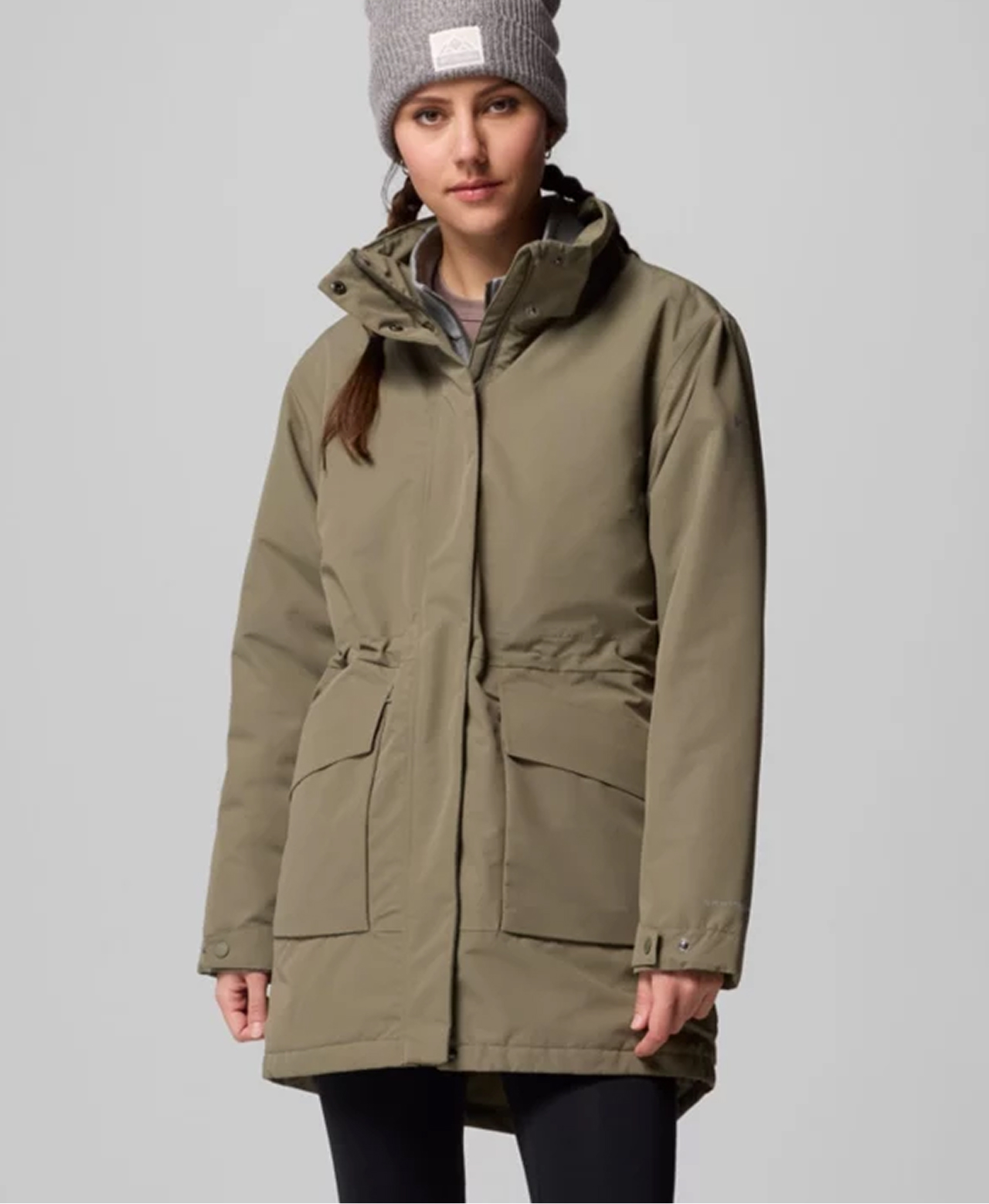 A woman wearing a green parka and grey hat.