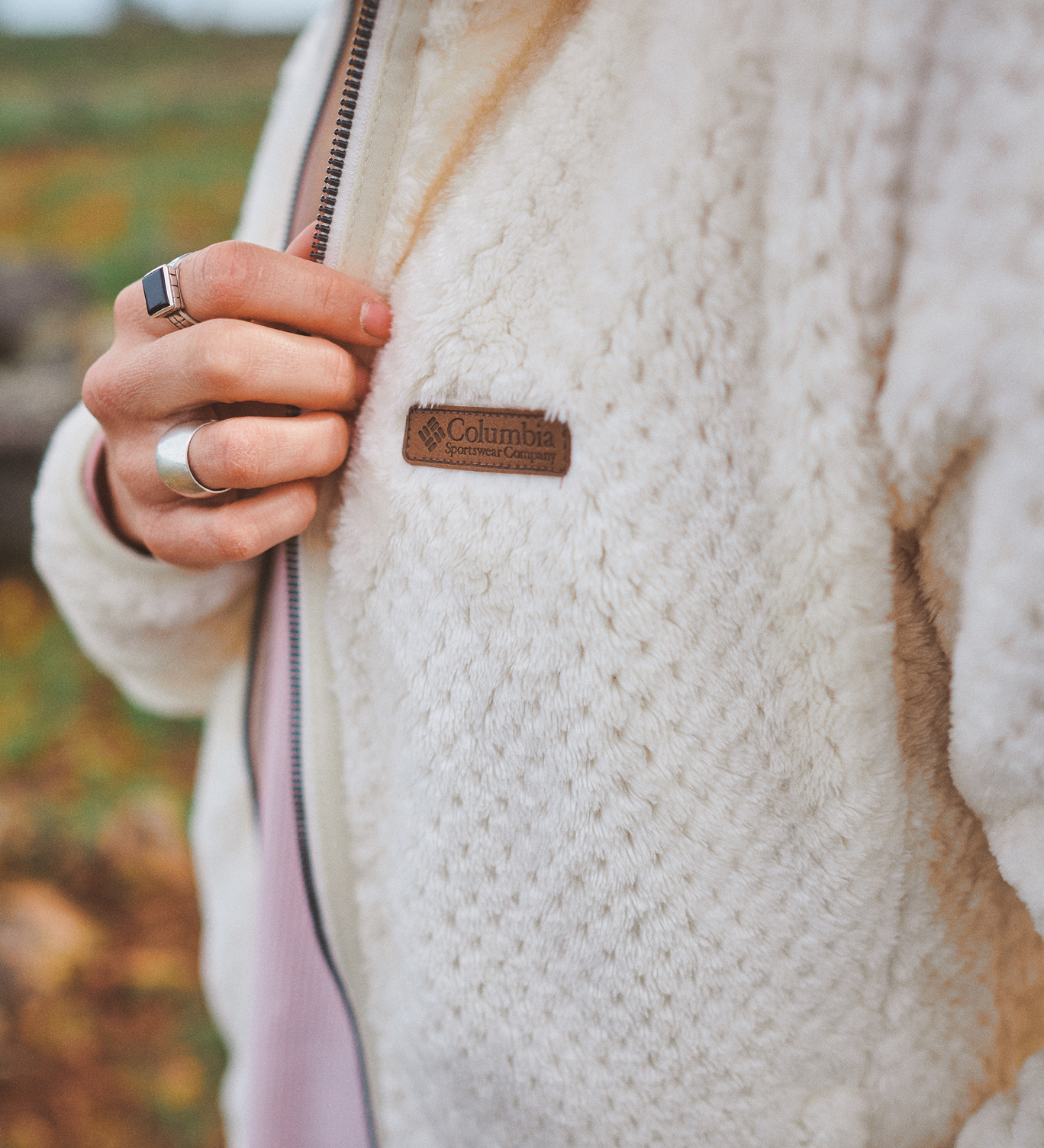 Close-up of a person's hand toughing the soft fleece exterior of their white plush jacket.