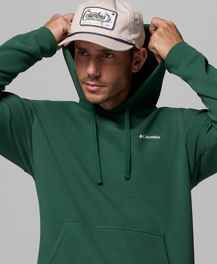 A man wearing a green hoodie, putting his hood up.