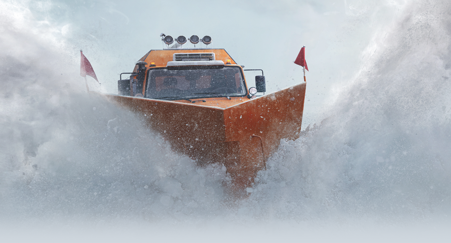An epic shot of a snow plow surrounded by powder.