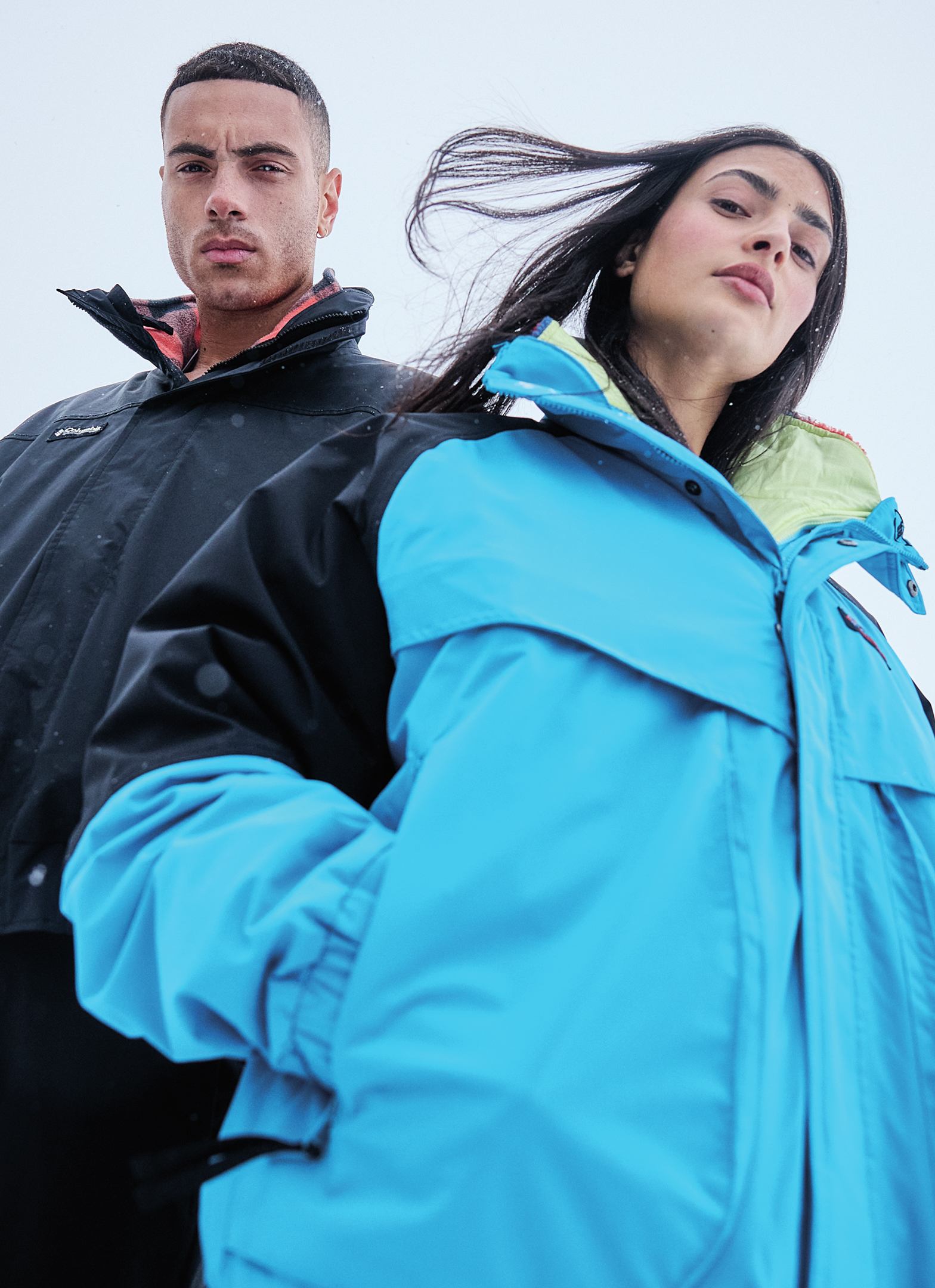 A man and woman wearing jackets outside with text: STAND UP TO WINTER