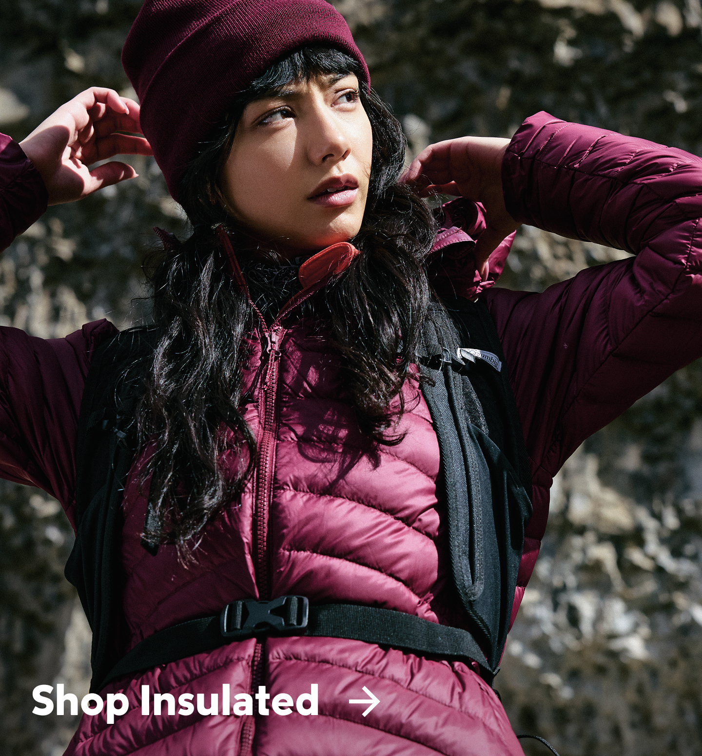 A woman wearing a puffy purple jacket with text: Shop Insulated