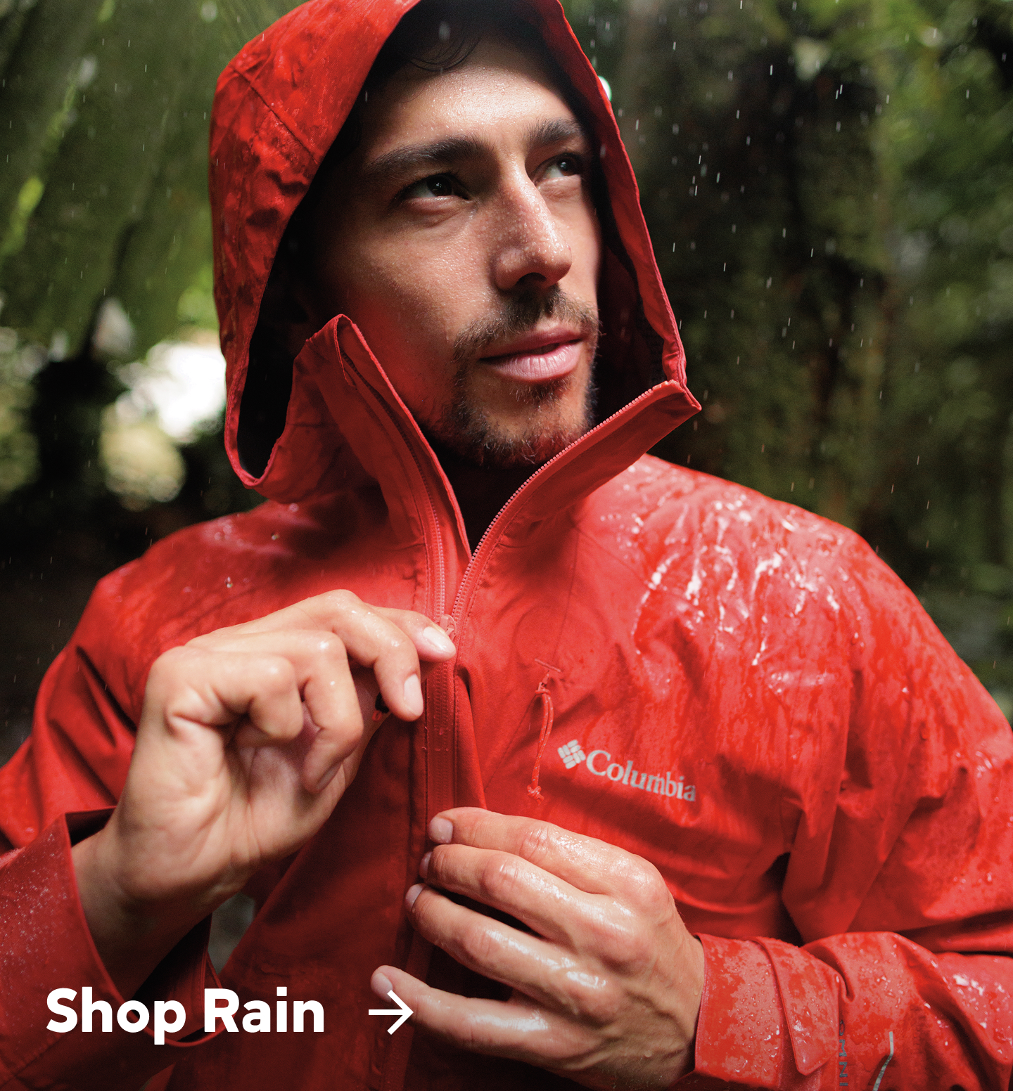 A man wearing a red rain jacket in the rain with text: Shop Rain