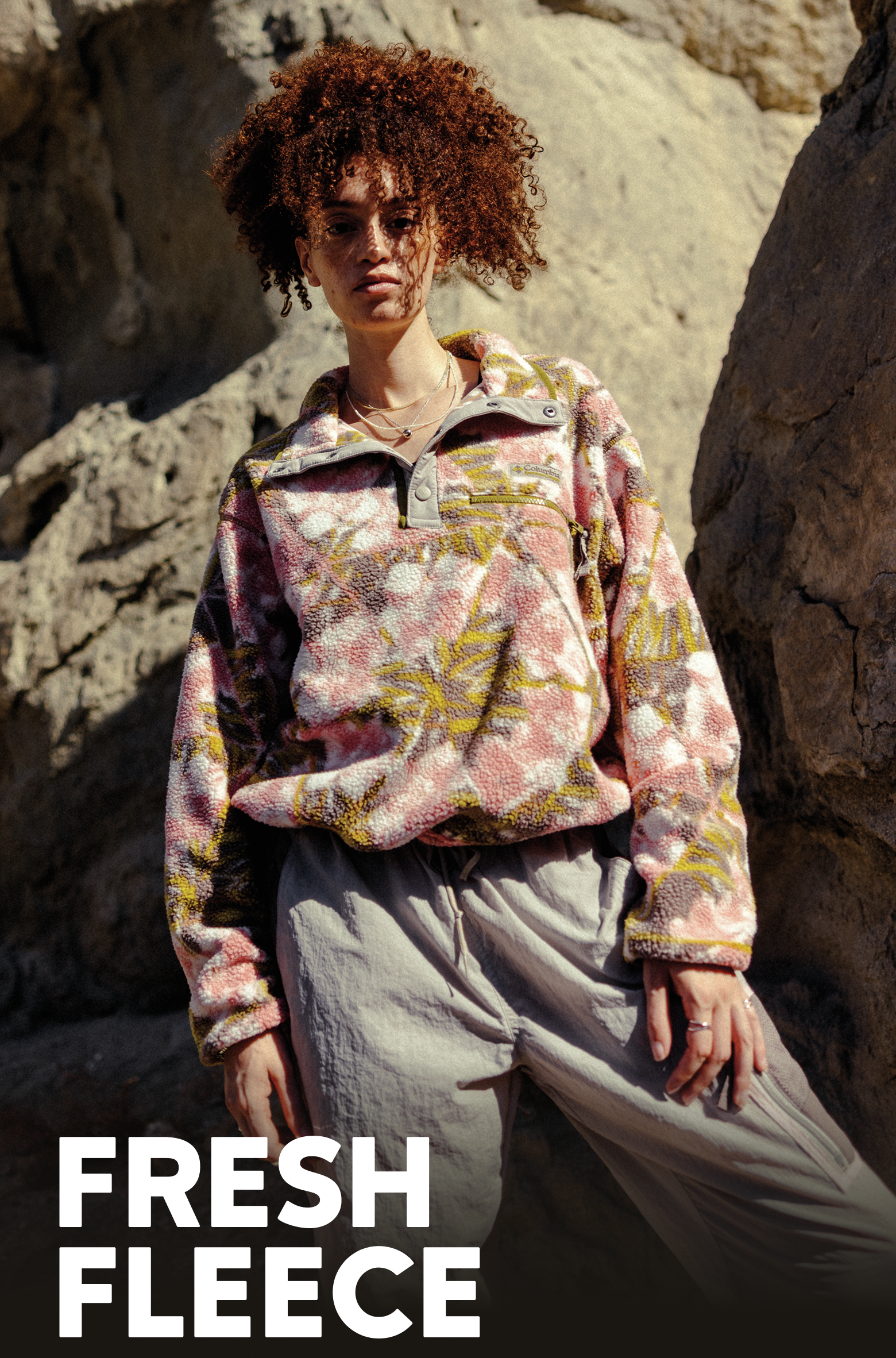 A woman wearing a printed fleece with a rocky wall behind her. Text says FRESH FLEECE
