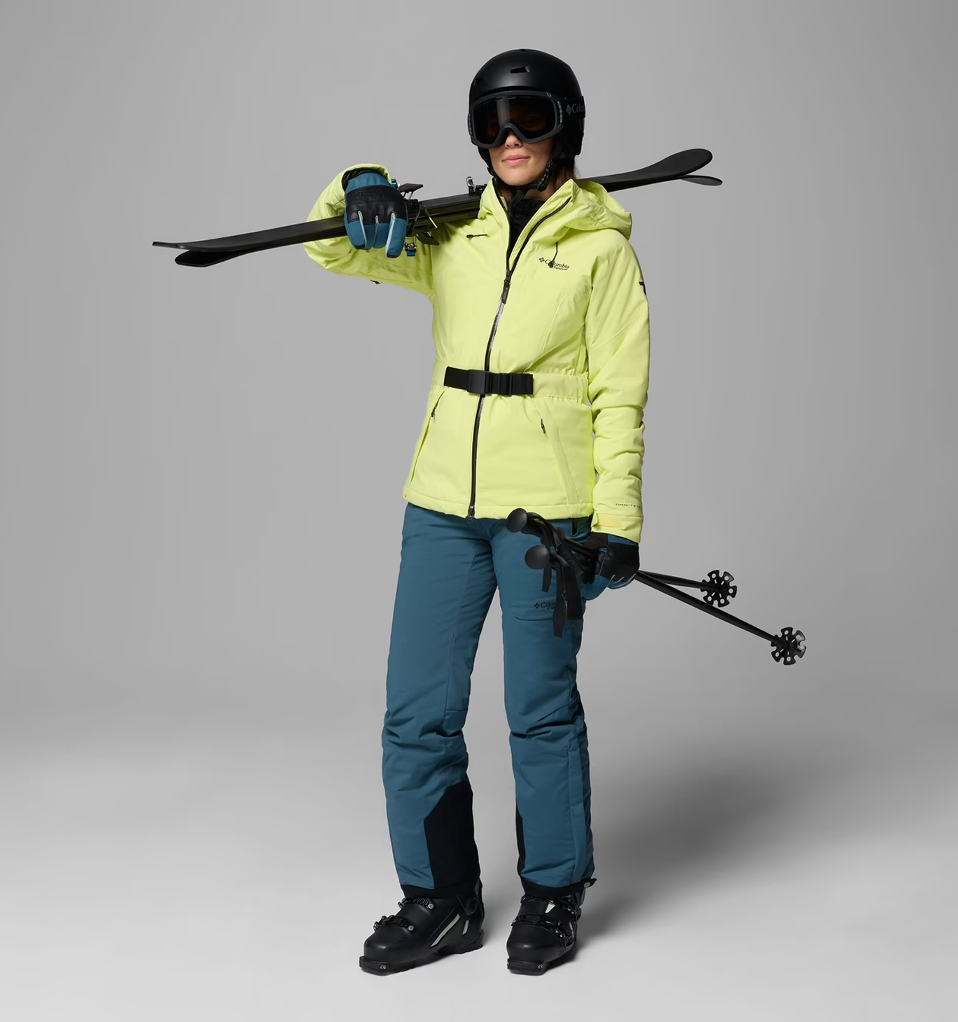 A woman wearing a purple ski jacket, black helmet, and goggles on.