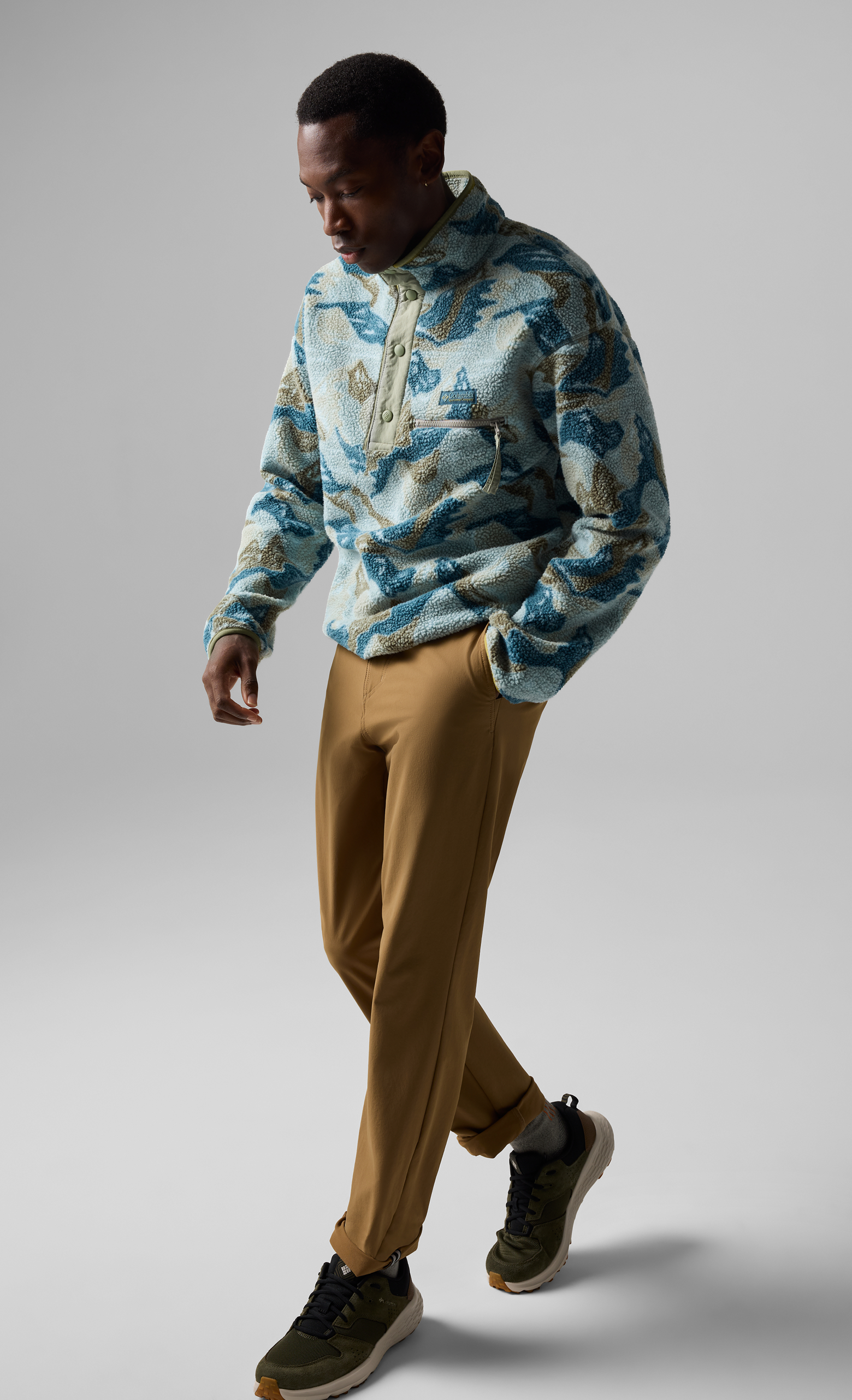 A man wearing a printed fleece and hiking pants.