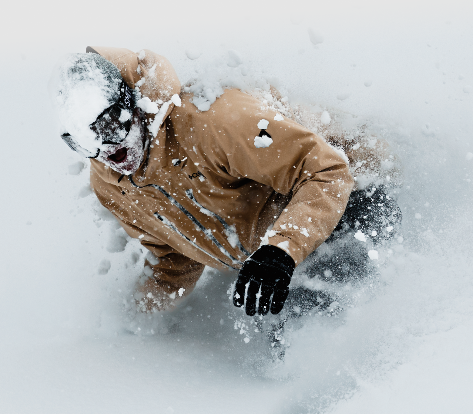 A snowboarder slashing through snow wearing Columbia 