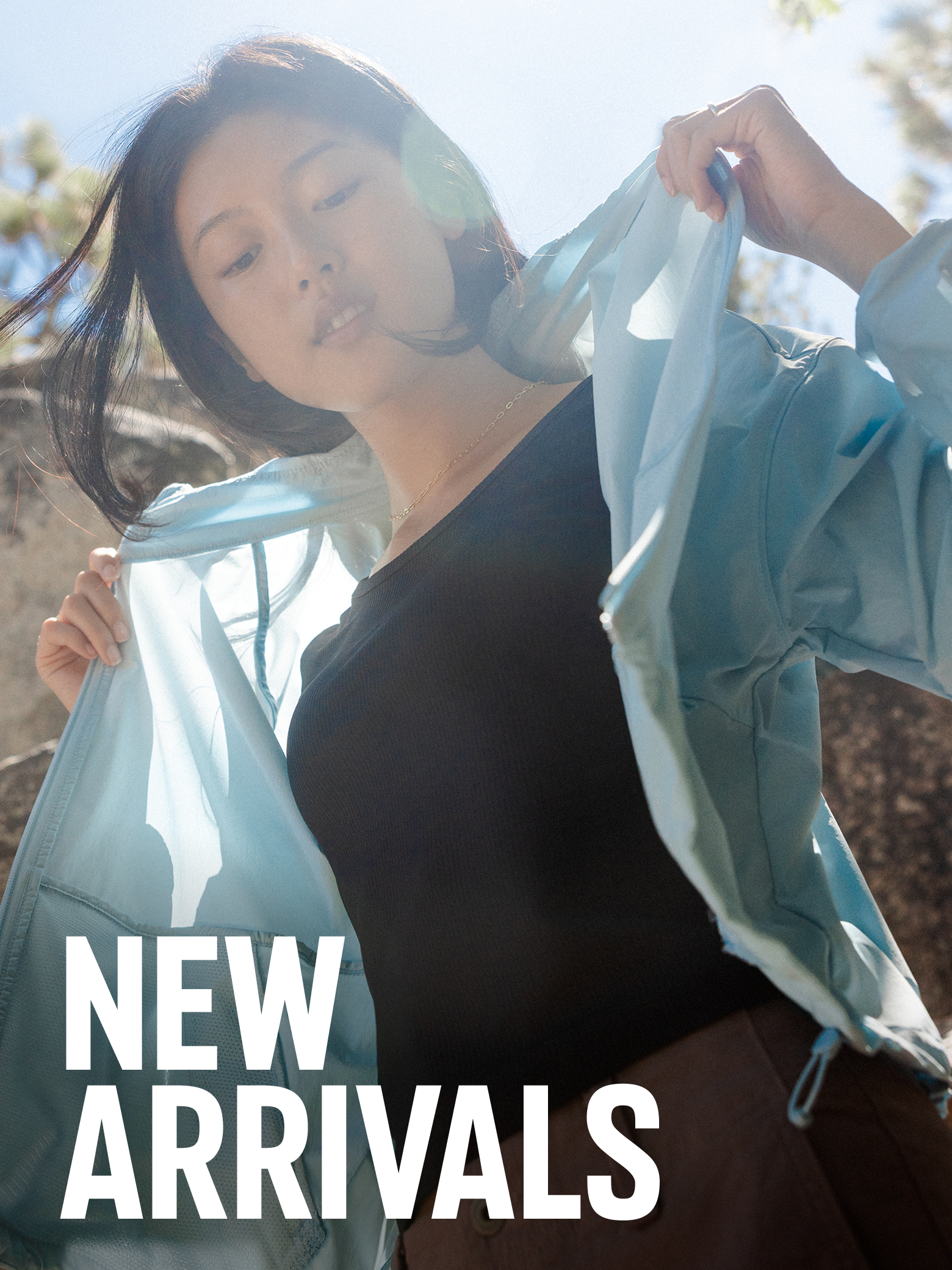 Woman wearing a blue lightweight jacket with text: New Arrivals