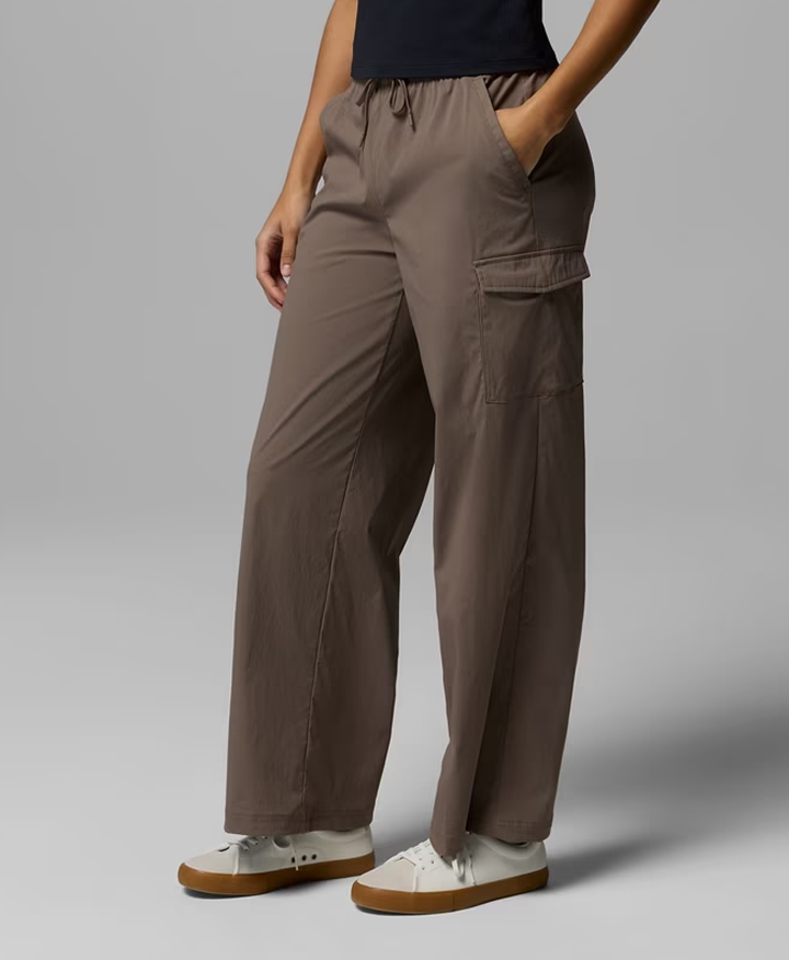 Waist-down image of a woman wearing dark grey-brown pants with white sneakers.