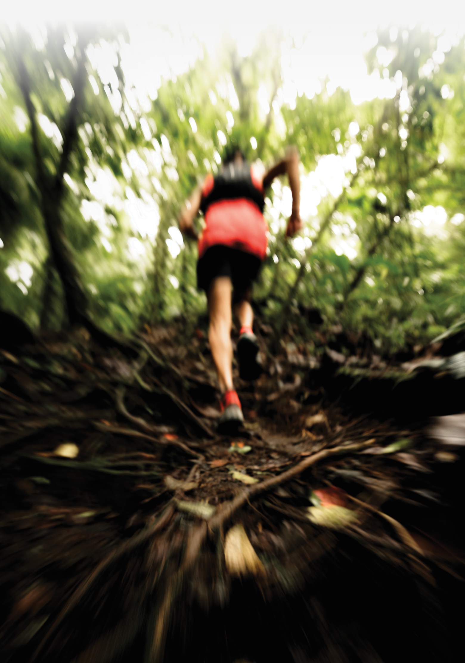 A runner in a red shirt, black shorts, and sneakers running away fast with a motion blur.