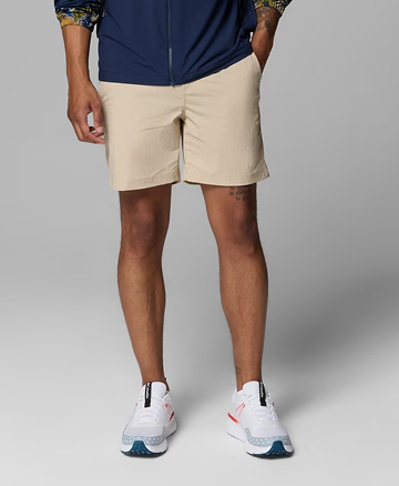 Waist-down image of a man wearing tan shorts and white sneakers.