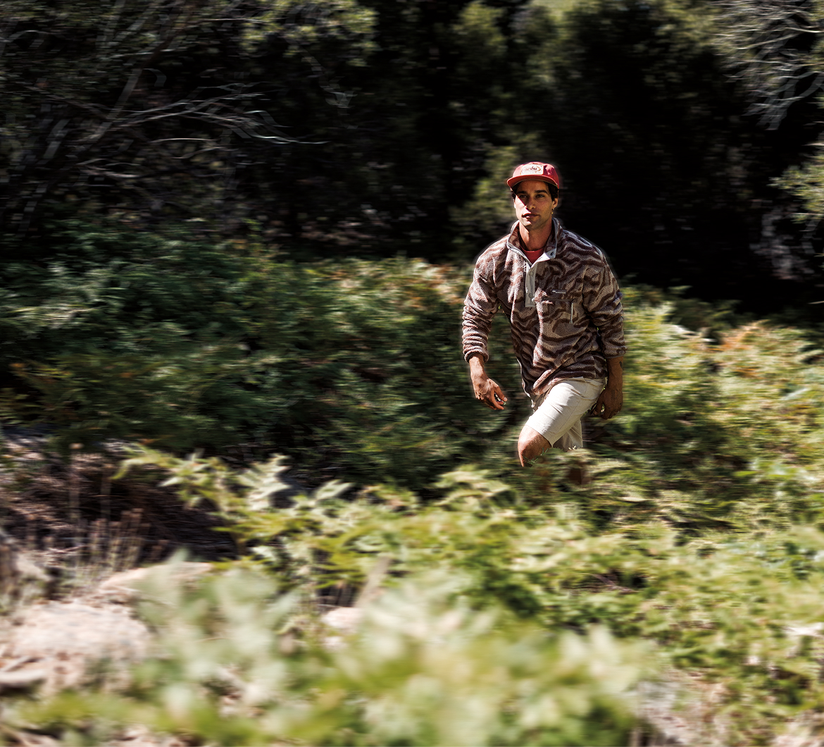 A slightly blurry photo of man in the distance walking through a forest with Helvetia fleece. 
