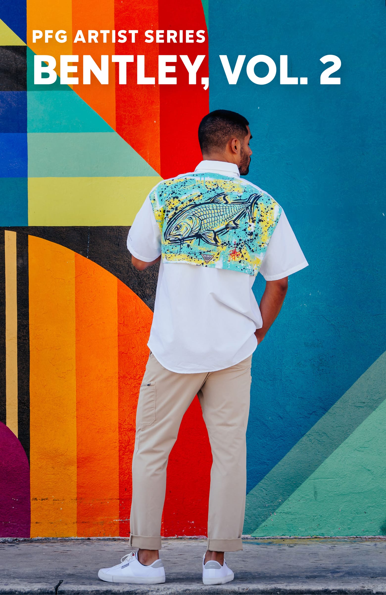 A man in a white shirt with a fish graphic on the back standing in front of colorful graffiti. PFG Artist Series Bentley Volume 2.