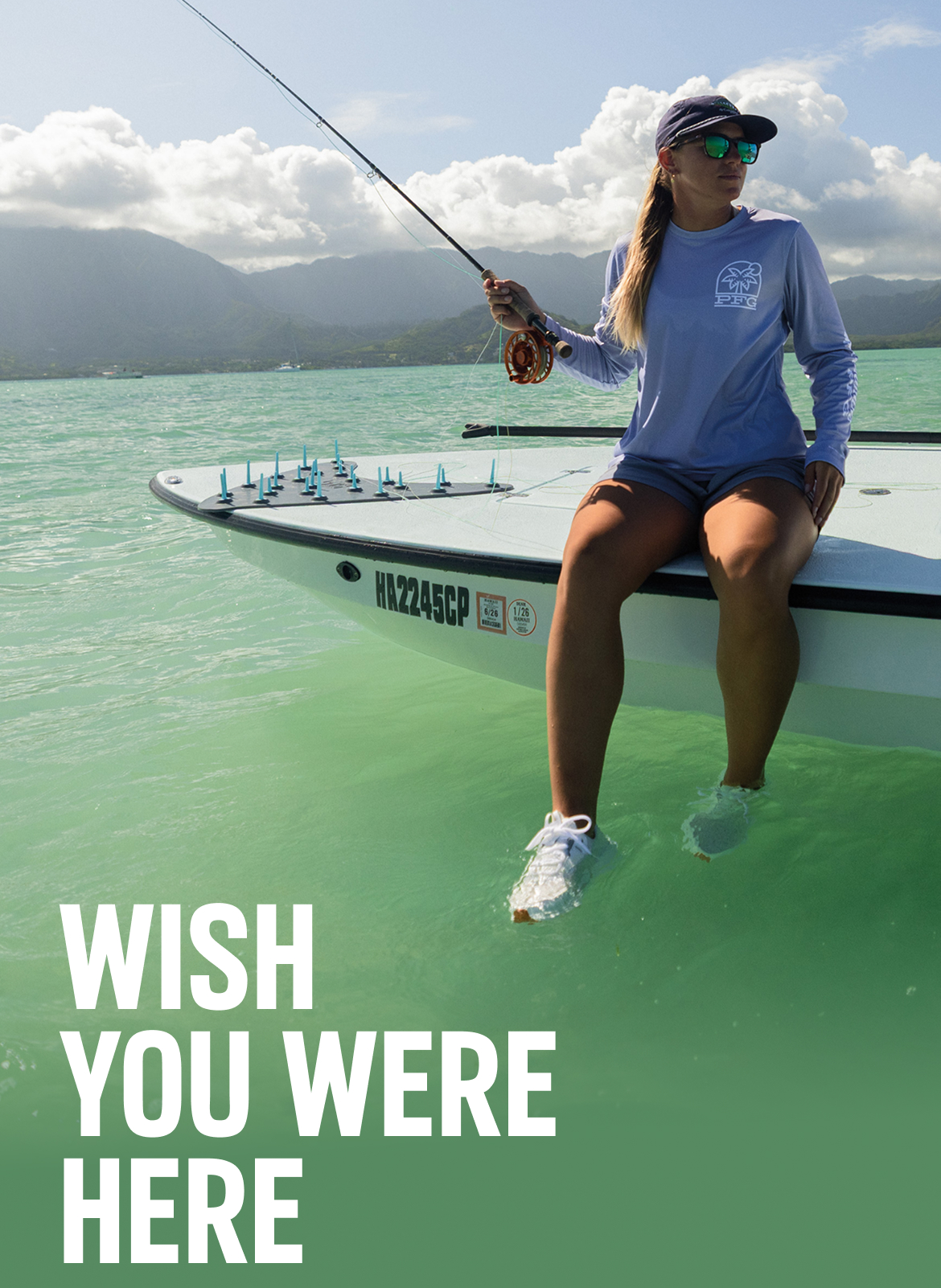 A woman sitting on a boat, letting her feet hang in the water, holding a fishing rod with text: WISH YOU WERE HERE