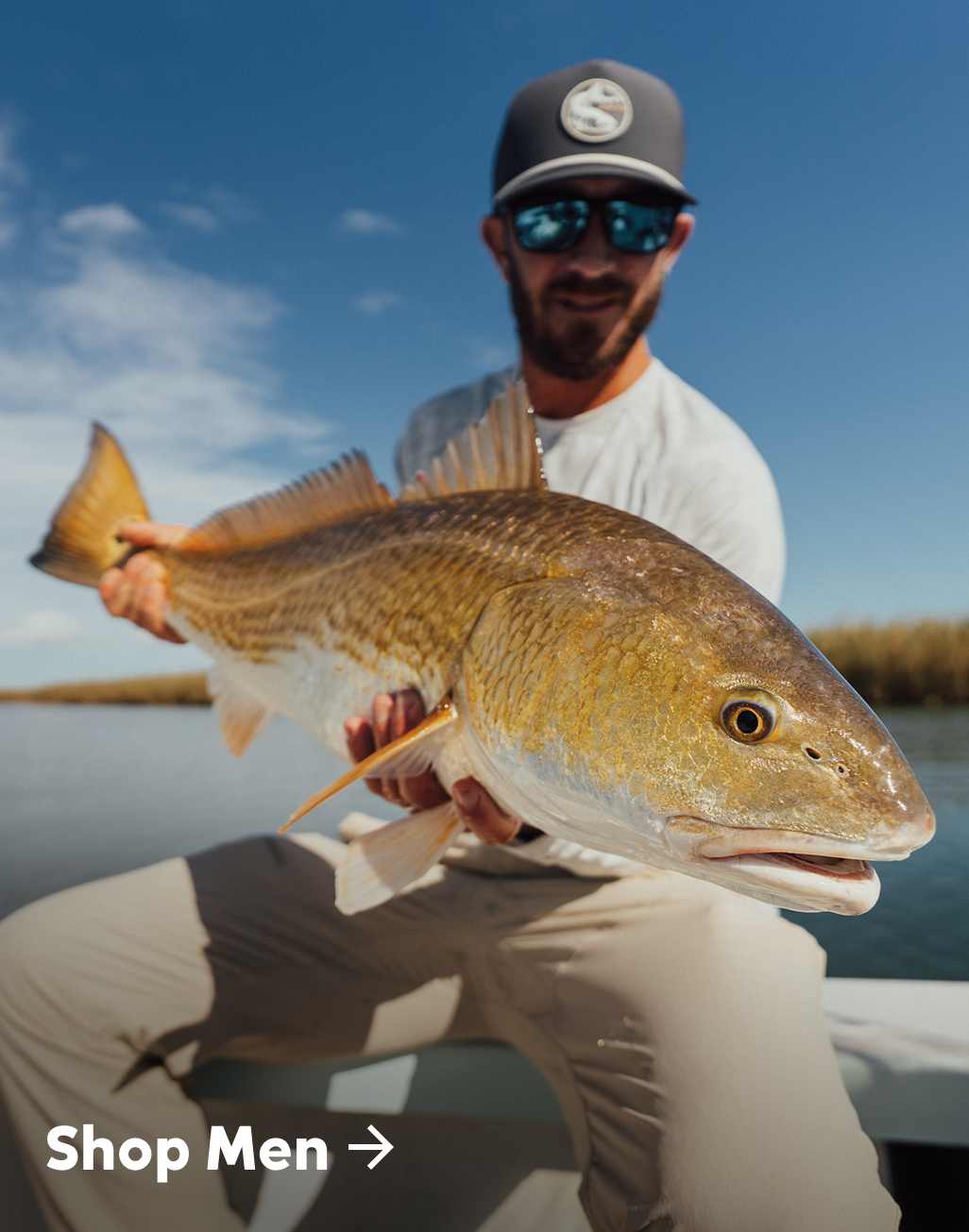 Man holds a fish while sitting in a boat.