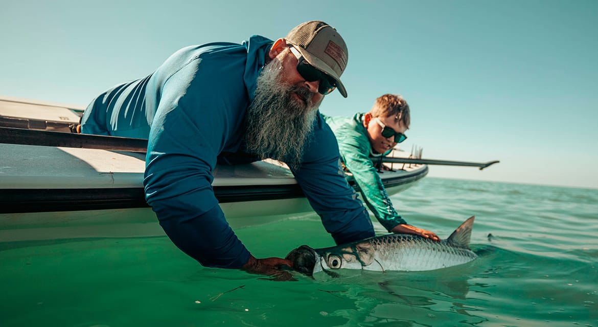 A father and son catching a fish. 