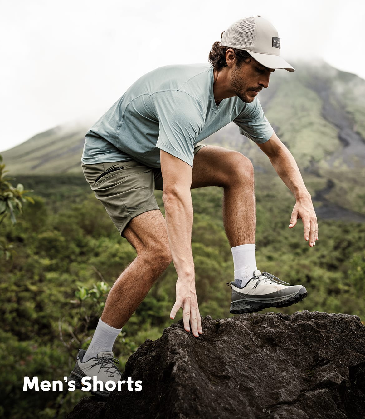A man scrambling over rocks with text that says Men's Shorts