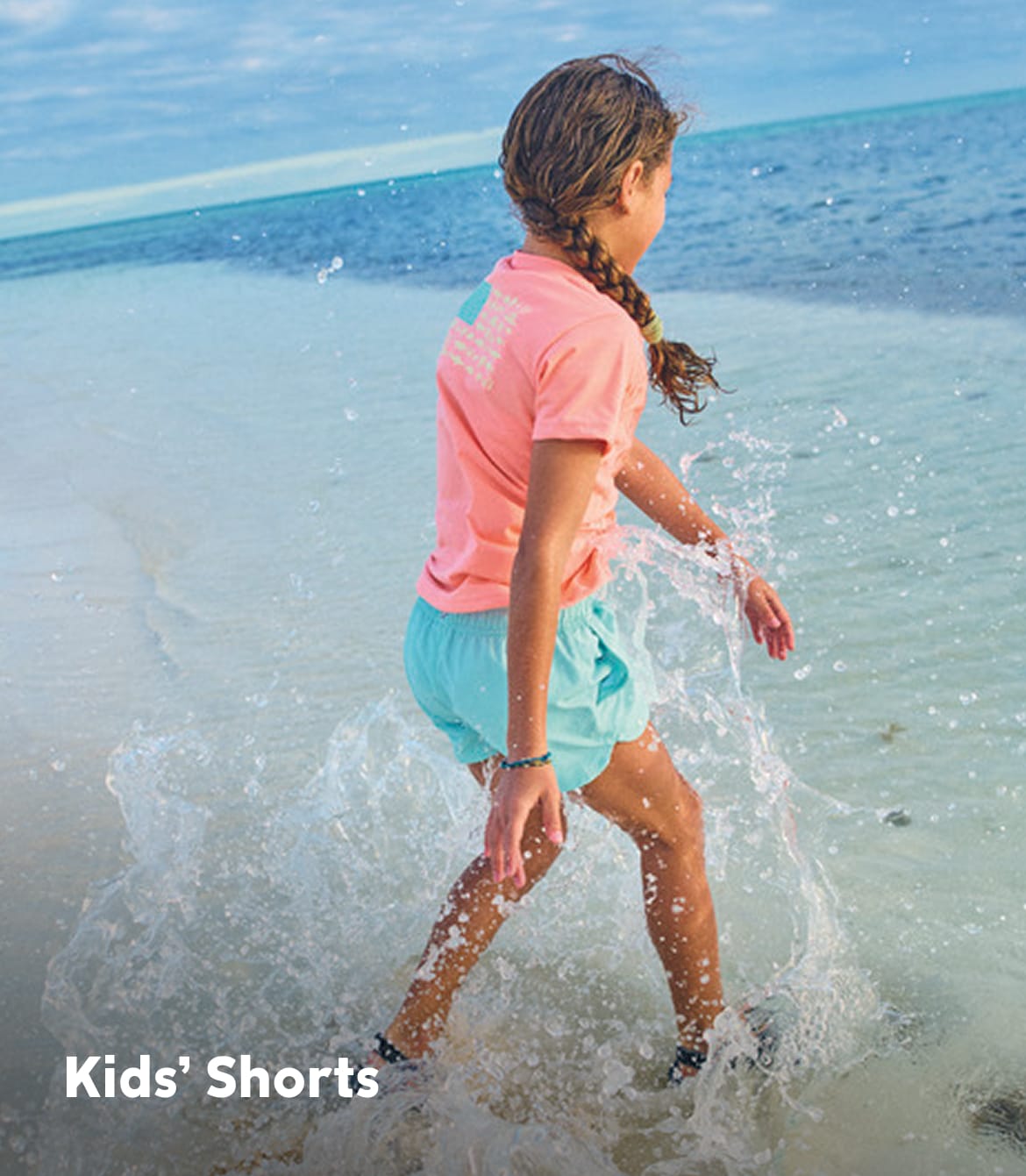A kid splashing on the beach with text that says Kids' Shorts