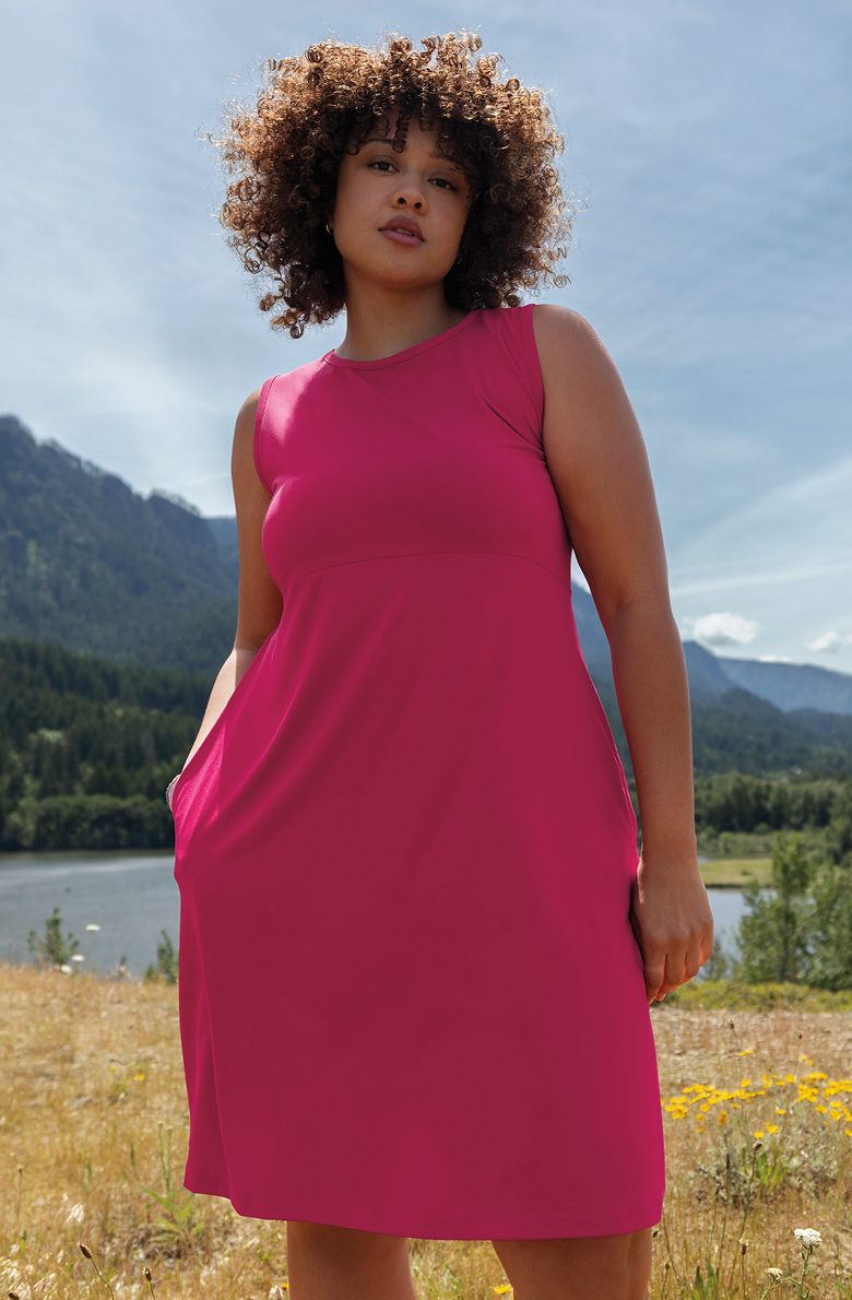 A woman standing in a field near a river while wearing a Columbia dress.
