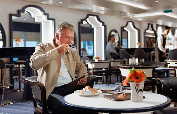 A cruise guest receiving a drink from waitstaff