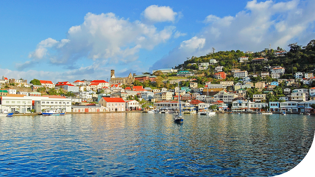 A serene body of water surrounded by buildings and boats, with trees lining the shore. The sky is partly cloudy, indicating a pleasant summer day in a resort town.