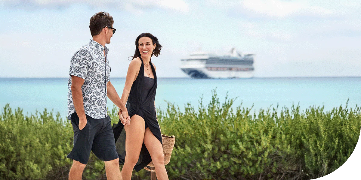 A Princess ship sails past 2 travellers on the beaches of Princess Cays, Caribbean.